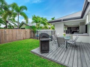 a backyard with a wooden deck with a table and chairs at Tropical Pool Sanctuary in Kewarra Beach, Family and Dog Friendly in Kewarra Beach +13 photos