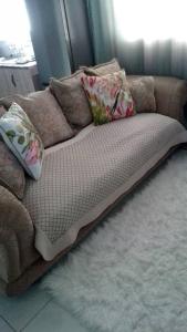 a brown couch with pillows on top of a white rug at Upendorest in Gaborone