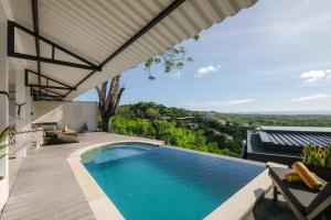 an outdoor swimming pool with a view of a house at Padawatu Villas in Uluwatu
