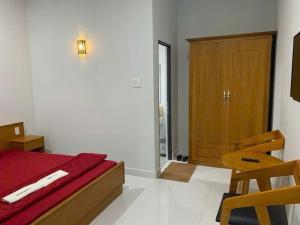 a bedroom with a red bed and a wooden cabinet at Khách sạn EDEN Chơn Thành in Chơn Thành