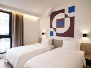two beds in a hotel room with a painting on the wall at Innk in Taichung