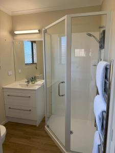 a bathroom with a shower and a sink at The Bach in Coromandel Town +8 photos