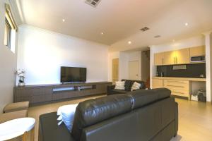 a living room with a leather couch and a flat screen tv at Marina Views Mindarie in Mindarie