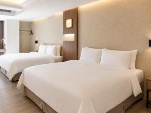 two beds in a hotel room with white sheets at Innk in Taichung +23 photos