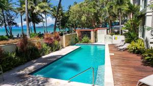 a swimming pool with a wooden deck next to a house at The Marron Bloom - Beachfront Boutique Bliss in Palm Cove