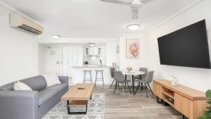a living room with a couch and a tv on a wall at 'The Sand Dollar' Central Cairns Chic with Adjacent Studio in Cairns