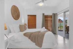 a white bedroom with a white bed and a window at 'Eclipse' A Poolside Family Escape in the CBD in Cairns