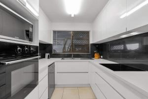 a white kitchen with a sink and a stove at 'Eclipse' A Poolside Family Escape in the CBD in Cairns