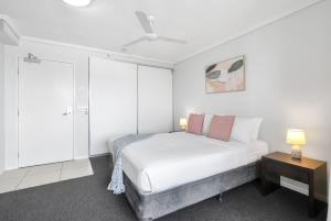 a white bedroom with a bed and a table at Peak Studio - Highview Haven across Shopping Centre in Cairns