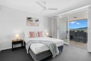 a white bedroom with a bed and a balcony at Peak Studio - Highview Haven across Shopping Centre in Cairns