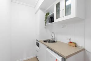 a kitchen with white cabinets and a sink at McLeod Nook - Poolside Studio by Waterfront & Market in Cairns