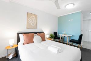 a bedroom with a white bed and two tables and chairs at McLeod Nook - Poolside Studio by Waterfront & Market in Cairns