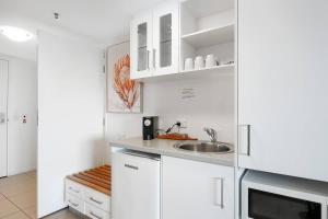 a kitchen with white cabinets and a sink at 'Seaside Azul' A Central Studio with Rooftop Pool in Cairns