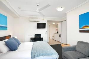 a bedroom with a bed and a couch and a tv at 'Seaside Azul' A Central Studio with Rooftop Pool in Cairns +4 photos