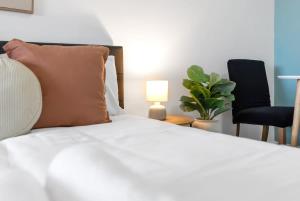 a bedroom with a white bed with a lamp and two chairs at McLeod Nook - Poolside Studio by Waterfront & Market in Cairns +11 photos
