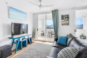 a living room with a couch and a flat screen tv at Cairns City Escape - Elevated Modern Haven with Pool in Cairns