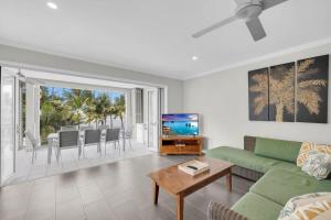 a living room with a green couch and a television at Turquesa Tides - Beachfront Resort Living in Palm Cove