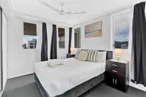 a white bedroom with a large bed and windows at McLeod Rise - Cairn Base with Rooftop Pool & Spa in Cairns