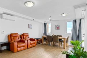 a living room with an orange chair and a table at McLeod Rise - Cairn Base with Rooftop Pool & Spa in Cairns