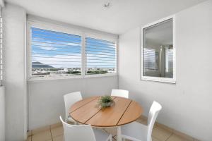 a dining room with a wooden table and white chairs at Cairns Central Adjacent Suites, Steps to Esplanade in Cairns