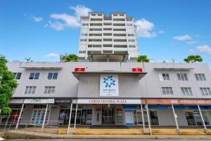a tall white building with a pharmacy in front of it at Cairns Central Adjacent Suites, Steps to Esplanade in Cairns