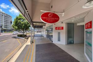 a building with a red sign on the side of it at Cairns Central Adjacent Suites, Steps to Esplanade in Cairns