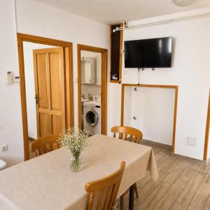 a dining room with a table with chairs and a television at Apartments Renato Mužić Cres in Cres