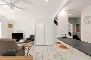 a living room with a couch and a clock on the wall at Tropical Cove at Trinity Beach with Lagoon Pool in Trinity Beach +8 photos