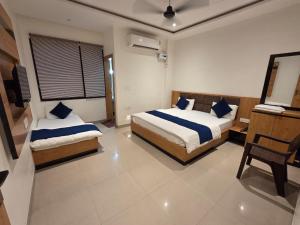 a bedroom with two beds and a desk in it at Vrind Orchid- Near Prem Mandir in Vrindāvan