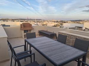 a patio with a table and chairs on a roof at Sunsets Duplex Penthouse Gozo in Kerċem