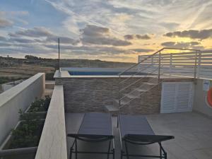 a patio with two stools and a staircase on a building at Sunsets Duplex Penthouse Gozo in Kerċem