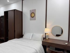 a bedroom with a bed and a desk and a mirror at The C'mon Mộc Châu in Làng Môn