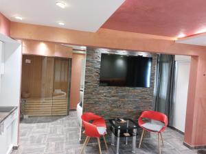 a living room with two red chairs and a flat screen tv at De Lux Apartment Maki in Banja Luka