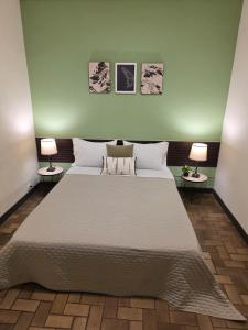 a bedroom with a large white bed with two lamps at Luca in San José