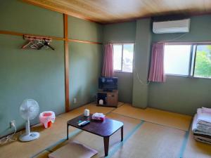 a living room with a table and a tv in it at 民宿 とうの浜 in Yasuda