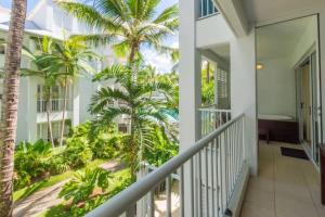 a balcony with palm trees in a house at Couple's Coastal Haven Retreat at The Beach Club in Palm Cove