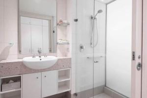 a white bathroom with a sink and a shower at Couple's Coastal Haven Retreat at The Beach Club in Palm Cove +8 photos