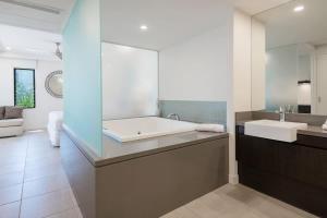 a bathroom with a large tub and a sink at Poolside Relaxation - Resort Retreat with Beach Access in Port Douglas