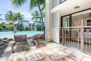 two chairs sitting on a patio next to a swimming pool at Poolside Relaxation - Resort Retreat with Beach Access in Port Douglas