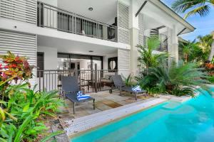 a house with a swimming pool and a balcony at Poolside Bliss: A Modern Resort Sanctuary in Port Douglas