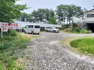 two cars parked in a gravel parking lot at 民宿 とうの浜 in Yasuda