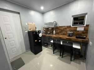 eine Küche mit Theke, Stühlen und Kühlschrank in der Unterkunft A Residences in Daet