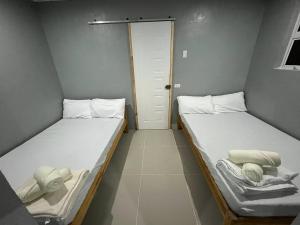 Zwei Einzelbetten in einem kleinen Zimmer mit Tür in der Unterkunft A Residences in Daet