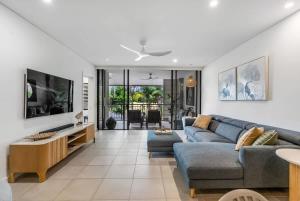 a living room with a blue couch and a tv at Rooftop Tranquility at Stunning Temple Resort in Port Douglas