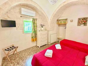 a living room with a red bed and a tv at Trulli Fenice in Martina Franca