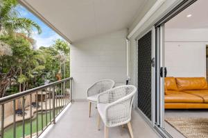 a balcony with two chairs and a couch at The Tropical Trinity - A Breezy Beachside Getaway in Trinity Beach