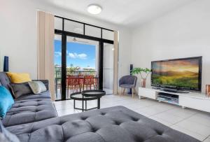 a living room with a couch and a flat screen tv at The Loft - Trendy Coastal Charm with Pool in Cairns