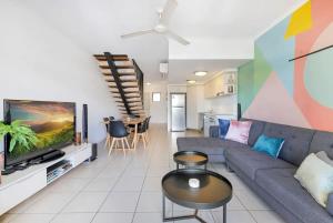 a living room with a couch and a tv at The Loft - Trendy Coastal Charm with Pool in Cairns