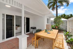 a patio with a wooden table and a bench at The Bird House - Poolside Haven a Stroll from Beach in Palm Cove