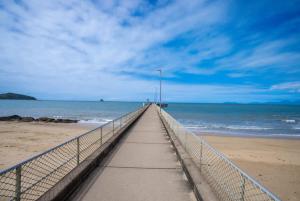 a boardwalk stretches out into the ocean on a beach at The Bird House - Poolside Haven a Stroll from Beach in Palm Cove +21 photos